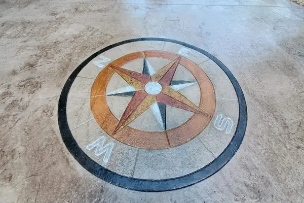 A compass rose medallion stamped and colored into a concrete floor.