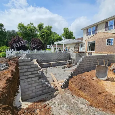 Block retaining walls going up in an excavated yard.