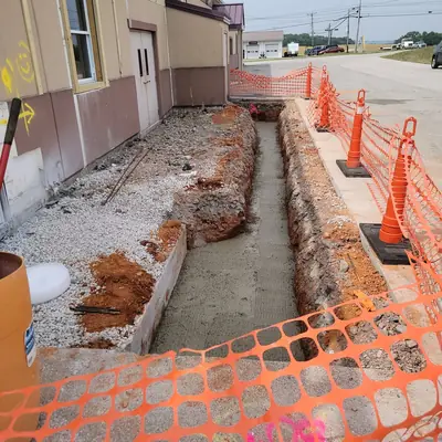 A drainage trench cut alongside a commercial building.