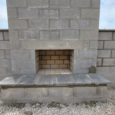 An outdoor block fireplace with a firebrick firebox and bluestone hearth.