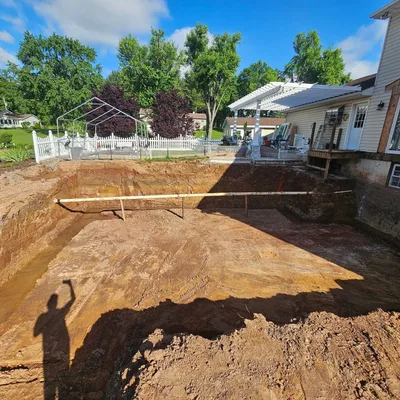 A large excavation dug into a back yard, running right up to the house foundation.
