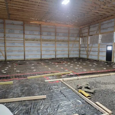 Wire mesh and vapour barrier laid out across a pole building floor before the pour.
