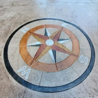 A compass rose medallion stamped into a concrete floor.
