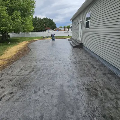 A stamped and colored concrete patio curving along the side of a house.