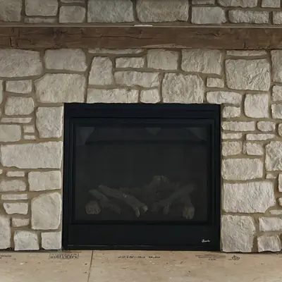 A coursed stone fireplace surround with a timber mantel and a firebox.